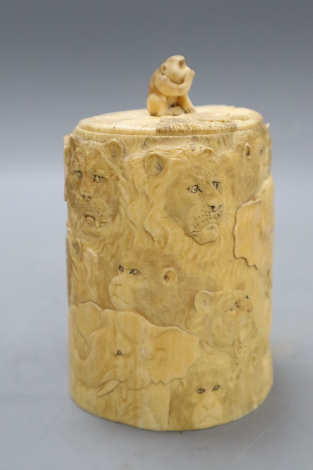 A Japanese ivory box and cover, Meiji Period, carved with elephants, lions, monkeys, etc. (lacking base), overall height including lid